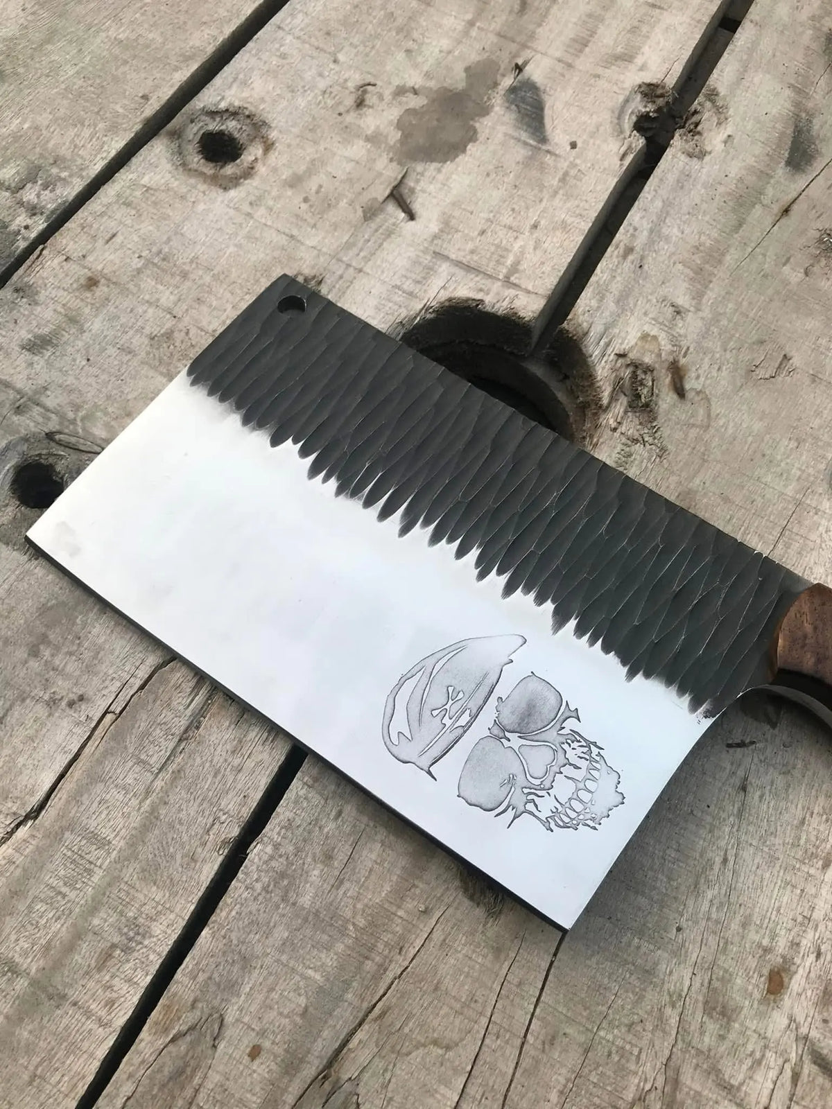 Hand engraved skull design on polished D2 steel chopper blade close-up