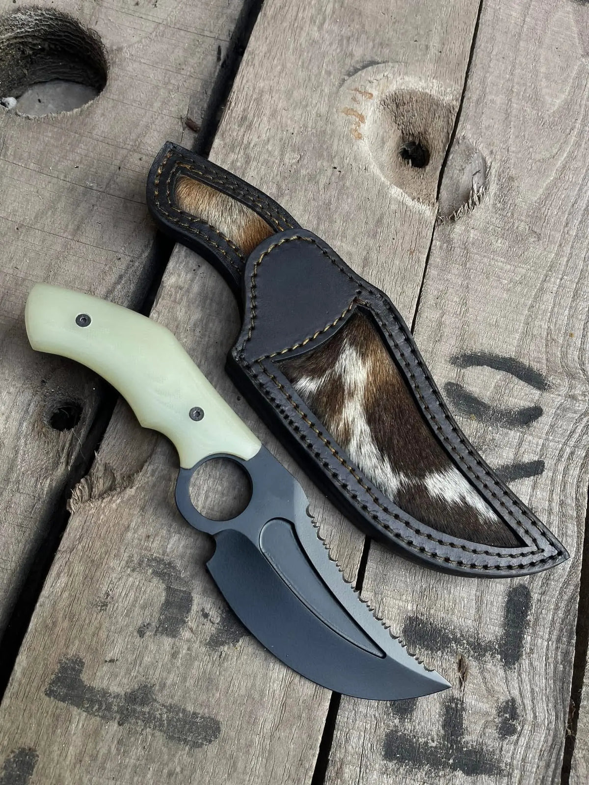 Black powder coat recurve blade with fuller and serrated section close-up