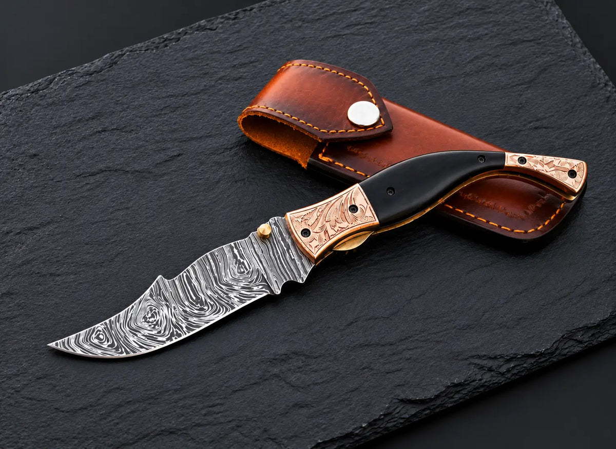Handmade Damascus folding knife with buffalo horn handle and engraved copper bolsters - full view with sheath