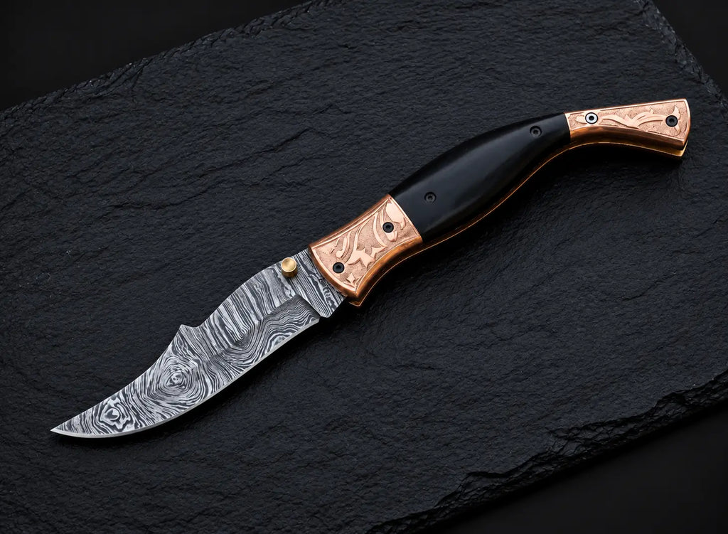 Engraved copper bolster floral design detail on Damascus folding knife