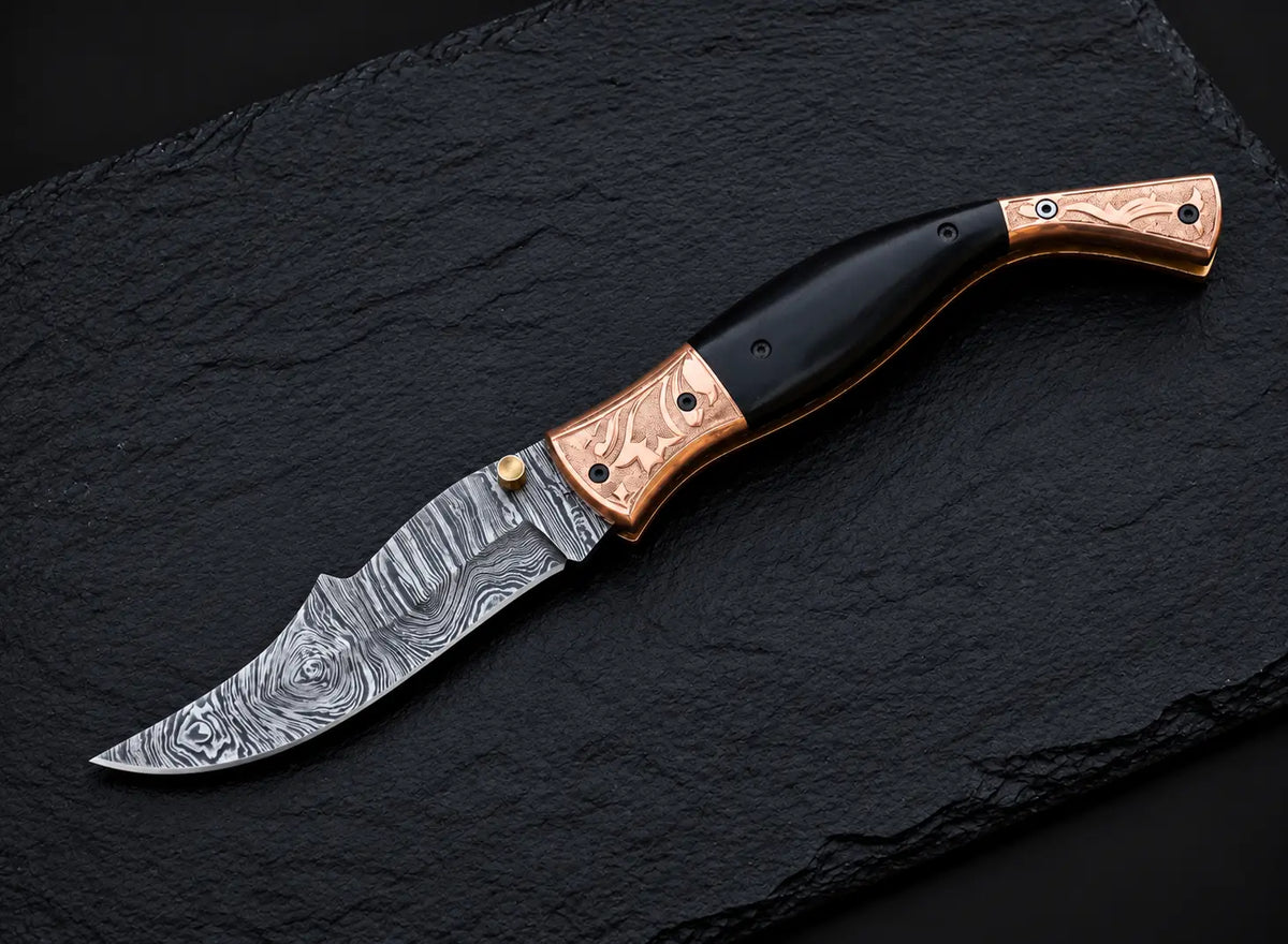 Engraved copper bolster floral design detail on Damascus folding knife
