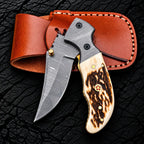 Stag horn handle with brass pins and red mosaic pin detail on Damascus folding knife