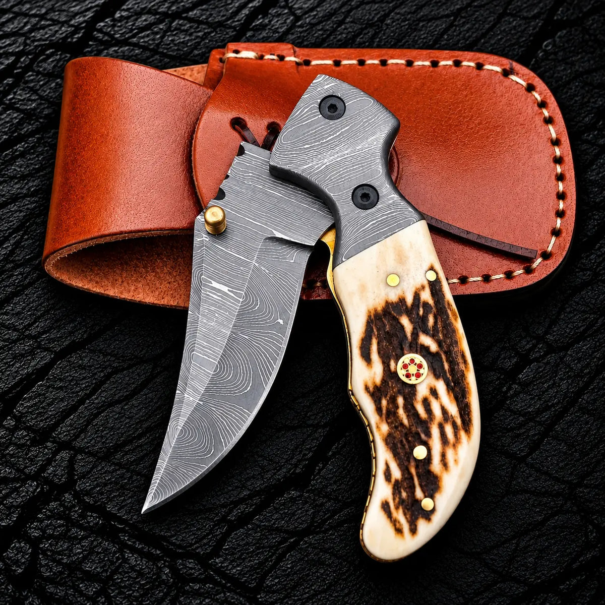 Stag horn handle with brass pins and red mosaic pin detail on Damascus folding knife