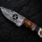 Feather Damascus blade with wire-cut deer head design and gut hook close-up
