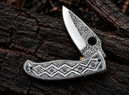 Geometric diamond and rosette engraved handle detail on steel folding knife